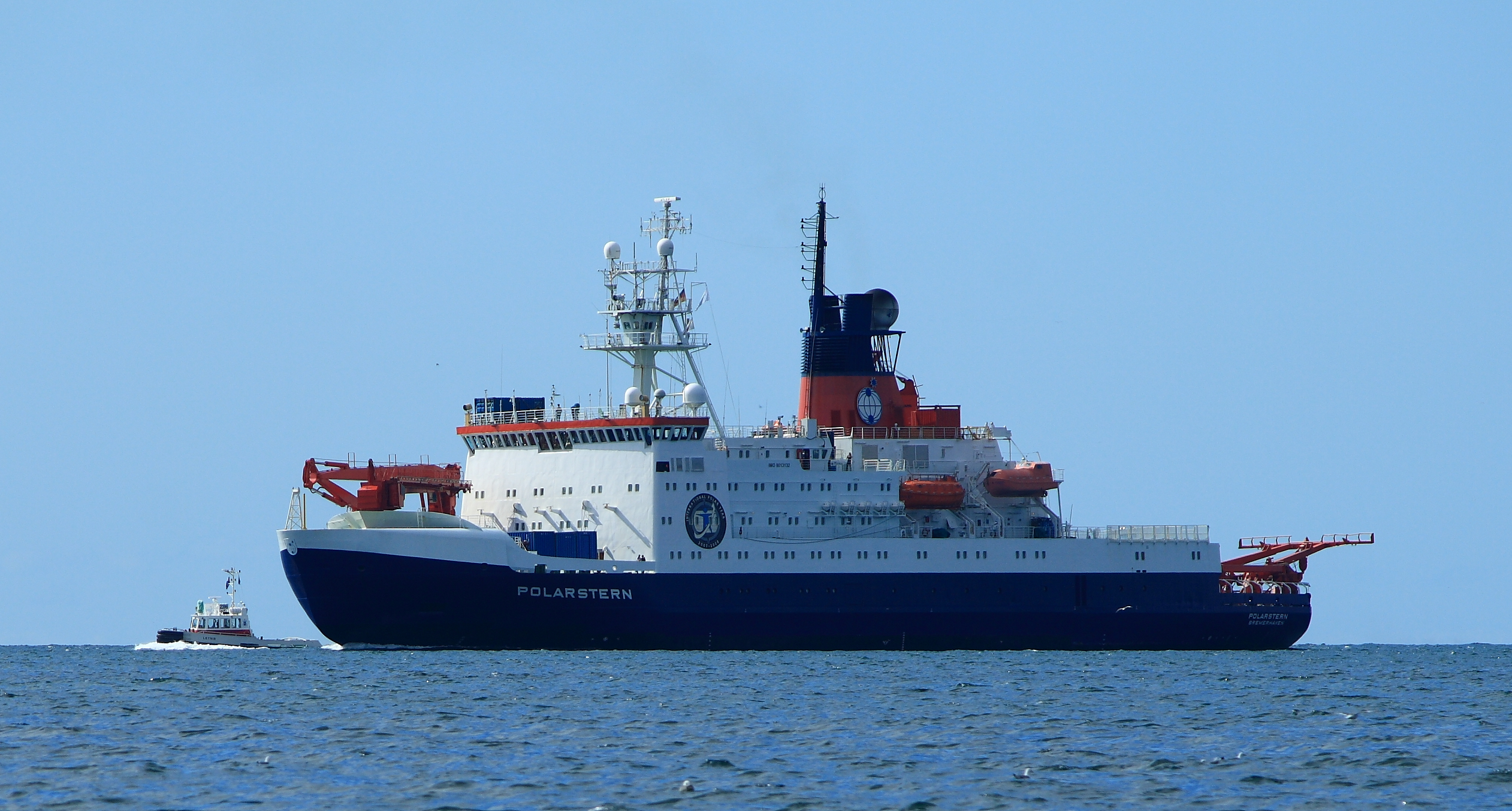 1) Kurzbeschreibung: Seitenansicht eines großen Schiffes mit dem Schriftzug „POLARSTERN“ mit blauem Rumpf und weißen Aufbauten.
<ol start=