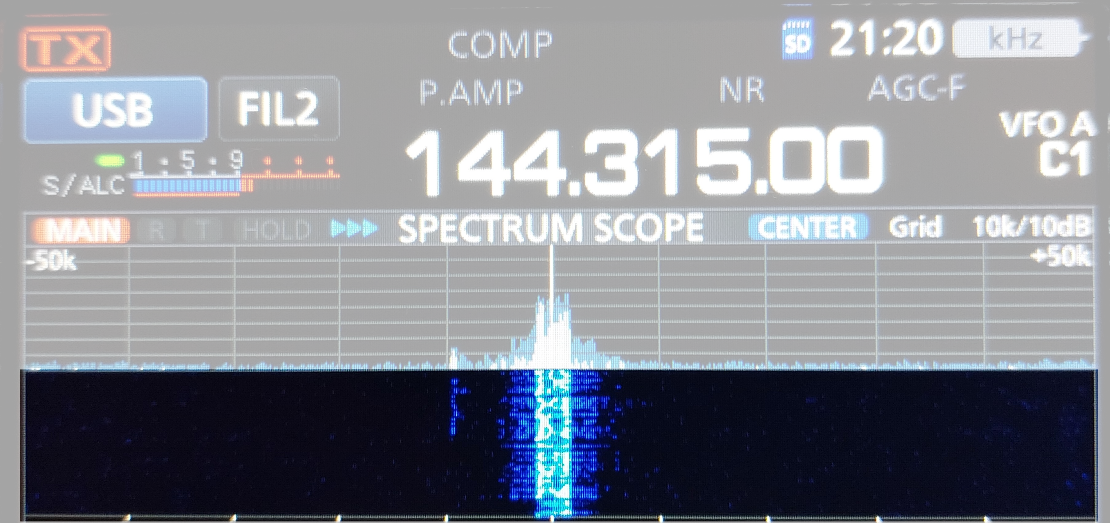 1) Kurzbeschreibung: Display eines Funkgerätes mit Frequenzanzeige „144.315.00“, Spektrums- und hervorgehobene Wasserfalldarstellung eines starken Signals in der Mitte.
<ol start=
