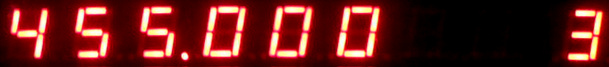 Dieser Alt-Text wurde noch nicht überprüft.
<p>Zusammenfassung: Eine rote Siebensegmentanzeige auf schwarzem Hintergrund zeigt die Zahlenfolge 455.000, rechts ist eine weitere, angeschnittene Ziffer zu sehen.</p>
<p>Detailbeschreibung: Das Bild ist ein schmaler, horizontaler Ausschnitt einer digital leuchtenden Anzeige mit roten Siebensegmentziffern vor schwarzem Hintergrund. Von links nach rechts sind deutlich die Ziffern 4, 5, 5 zu sehen, gefolgt von einem leuchtenden Dezimalpunkt und drei Nullen (0 0 0). Die Segmente strahlen leicht über, wodurch ein weicher roter Glanz um die Balken entsteht. Am rechten Bildrand ist der linke Teil einer weiteren Ziffer angeschnitten, deren Form nicht vollständig erkennbar ist.">
<figcaption>Abbildung EA-10.25.1: Display eines Frequenzzählers, der $\qty{455}\cdot 10^3 Hz$ anzeigt</figcaption></p>
</figure>
</aside>
<aside class=