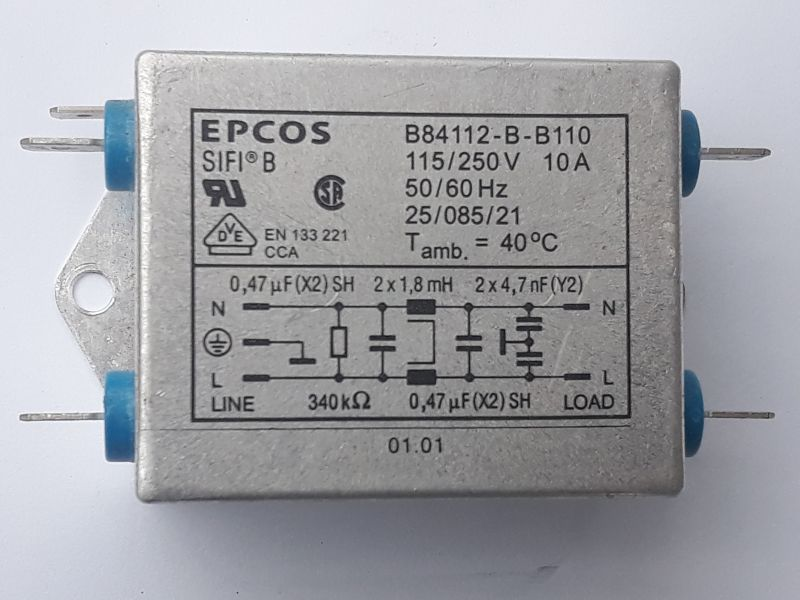 Dieser Alt-Text wurde noch nicht überprüft.
<ol>
<li>
<p>Kurze Zusammenfassung:
Rechteckiges, silbernes EPCOS-Bauteil im Metallgehäuse mit aufgedruckten technischen Daten und Schaltbild; an beiden Seiten ragen je zwei Anschlüsse durch blaue Isolatoren heraus.</p>
</li>
<li>
<p>Detaillierte Beschreibung:
Das Foto zeigt frontal ein graues/silbernes Metallgehäuse mit abgerundeten Kanten und einer seitlichen Befestigungslasche mit rundem Loch links. Links und rechts sind jeweils zwei flache Anschlussfahnen zu sehen, die durch blaue Isolatoren geführt werden. Auf der Gehäusefront steht oben links „EPCOS“ und „SIFI B“. Oben rechts sind Typ- und Leistungsdaten aufgedruckt: „B84112-B-B110“, „115/250V 10A“, „50/60 Hz“, „25/085/21“, „T amb. = 40°C“. Darunter befinden sich mehrere Prüf- und Normzeichen (u. a. ein „UR“-Symbol, ein rundes „CSA“-ähnliches Zeichen und ein Dreieck mit „VDE“), sowie der Text „EN 133 221 CCA“. In einem eingerahmten Feld ist ein Schaltbild mit Beschriftungen dargestellt: links „LINE“ mit „N“ und „L“, rechts „LOAD“ mit „N“ und „L“; eingezeichnet sind Kondensatoren und Drosseln, beschriftet u. a. mit „0,47 µF (X2) SH“, „2 x 1,8 mH“, „2 x 4,7 nF (Y2)“ und ein Widerstand „340 kΩ“. Links neben dem Schaltbild ist das Erdungssymbol abgebildet. Unten mittig steht „01.01“. Die Oberfläche wirkt matt und leicht gebürstet; Hintergrund ist neutral hell."></p>
 <figcaption>Abbildung A-5.9.5:  Funkentstörfilter Filter für ein Schaltnetzteil</figcaption>
</li>
</ol>
</figure>
<figure class=