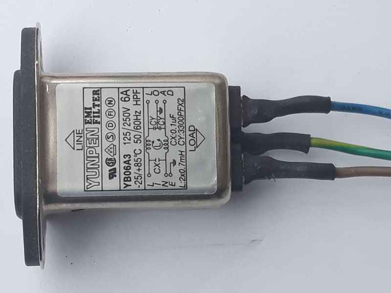 Dieser Alt-Text wurde noch nicht überprüft.
<ol>
<li>
<p>Kurze Zusammenfassung: Ein rechteckiges EMI‑Filter im Metallgehäuse mit Typenschild liegt auf weißem Hintergrund; rechts führen drei isolierte Adern (blau, gelb‑grün, braun) aus dem Gerät.</p>
</li>
<li>
<p>Detaillierte Beschreibung: Das silbern glänzende, rechteckige Gehäuse hat links einen schwarzen Montageflansch; auf der Oberseite befindet sich ein Etikett mit der Aufschrift „YUNPEN EMI FILTER“, Modell „YB06A3“, Nennwerten „6A“, „125/250V“, „50/60Hz“, Temperaturbereich „−25 bis +85°C“ sowie mehreren Prüf- und Zulassungszeichen. Ein Pfeil mit „LINE“ zeigt zum Flansch, ein Pfeil mit „LOAD“ nach rechts. Auf dem Etikett ist ein Schaltbild mit Bauteilangaben zu sehen, darunter „Lx: 2×0.7mH“, „Cx: 0.1µF“, „Cy: 2×3300pF X2“, mit Anschlusskennzeichnungen L, N und Erde-Symbol. Rechts treten drei Adern aus dem Gehäuse aus, jeweils mit schwarzem Schrumpfschlauch am Austritt; die Adern sind von oben nach unten blau, gelb‑grün und braun und verlaufen leicht nach rechts. Das Metall zeigt kleine Kratzer und matte Stellen; der Hintergrund ist eine glatte, weiße Fläche."></p>
 <figcaption>Abbildung NEA-14.18.1: Netzfilter</figcaption>
</li>
</ol>
</figure>
<figure class=