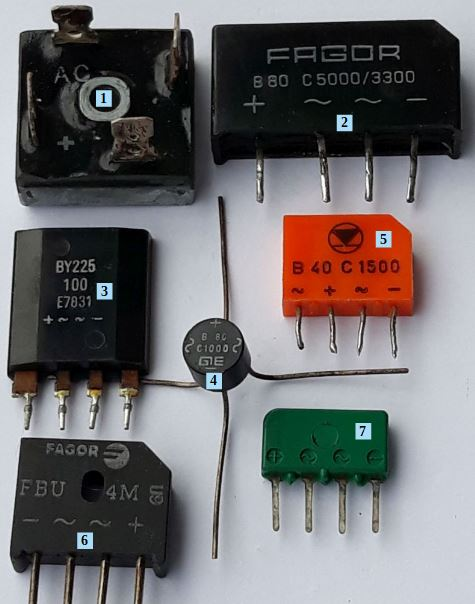Dieser Alt-Text wurde noch nicht überprüft.
<p>Kurzfassung: Auf weißem Hintergrund liegen mehrere verschiedenfarbige elektronische Bauteile mit Anschlussdrähten und aufgedruckten Symbolen (+, −, ~), teils mit blauen Nummernkästchen (1, 2, 4, 5, 6, 7) markiert.</p>
<p>Details:</p>
<ul>
<li>Oben links (1): Schwarzer, annähernd quadratischer Block mit zentraler runder Metallbuchse; Aufdruck „AC“, sowie „+“ und „−“ auf der Vorderseite.</li>
<li>Oben rechts (2): Schwarzes, rechteckiges Gehäuse mit vier nach unten zeigenden Pins; Aufdruck „FAGOR B80 C5000/3300“ und Symbole „~“, „+“, „−“.</li>
<li>Mitte links (ohne Nummer): Schwarzes, rechteckiges Bauteil mit vier Pins; Aufdruck „BY225 100 E7033“ sowie Symbole „~“, „+“, „−“.</li>
<li>Bildmitte (4): Kleines rundes, schwarzes Bauteil (Scheibenform) mit vier langen, kreuzförmig abstehenden Drähten; Aufdruck u. a. „GIE C1000C“.</li>
<li>Rechts daneben (5): Orangefarbenes, rechteckiges Gehäuse mit vier kurzen Pins; Aufdruck mit Logo und „B 40 C 1500“ sowie Polaritäts- und Wechselspannungssymbole.</li>
<li>Unten links (6): Schwarzes, trapezförmiges Gehäuse mit vier Pins; Aufdruck „FAGOR FBU 4M“ und Symbole für „+“ und „−“.</li>
<li>Unten rechts (7): Grünes, rechteckiges Bauteil mit vier Pins; kleine runde Vertiefungen oben und Aufdruck mit „+“, „−“ und „~“-Symbolen.</li>
<li>Zusätzlich: Ein einzelner, langer, dünner Draht verläuft im Zentrum vertikal nach oben.">
  <figcaption>Abbildung A-5.6.4:  Bauformen von Brückengleichrichtern</figcaption>
</li>
</ul>
</figure>
Die Beschriftung der Anschlüsse ist zu beachten.
<ol>
<li>Hochstrom-Brückengleichrichter 26 MB 20 A ($200 V$, $25 A$) im Metallgehäuse zur direkten Montage auf einem Kühlkörper</li>
<li>B80 C 5000/3300 bedeutet: maximal $80 V$ Betriebsspannung, C kapazitive Last max. $2500 µF$ mit Schutzwiderstand $R = 1 Ω$, maximaler Dauerlaststrom: $5000 mA$ mit Kühlkörper, $3300 mA$ ohne Kühlkörper</li>
<li>BY 225 Brückengleichrichter - besonderes Gehäuse</li>
<li>runde Bauform eines Brückengleichrichters B 80 C 1000</li>
<li>B40 C 1500 - die veränderte Anschlussfolge ist zu beachten</li>
<li>FPU 4M ($1000 V$, $4 A$)</li>
<li>im Kunststoff eingeprägte Anschlussfolge</li>
</ol>
</aside>

                        </div>
                    </article>
                </main>

                <aside class=