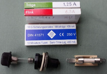 1) Kurzbeschreibung: Foto mit drei Feinsicherungen mit unterschiedlicher Auslösezeit in Verpackungen sowie zwei Sicherungshalter.
<ol start=